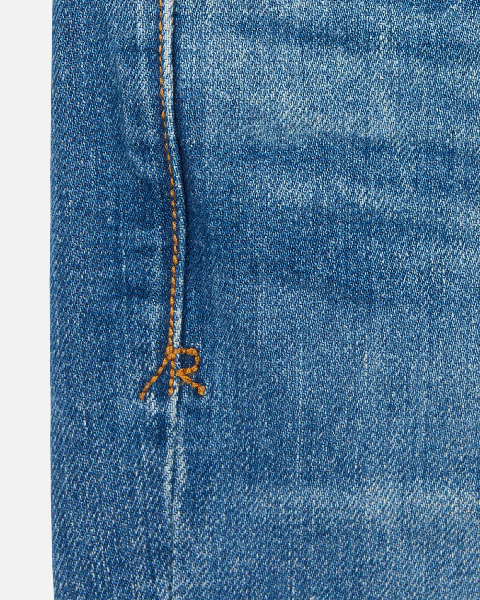 close up of stitching on pair of men's athletic taper medium light blue jeans with slight wear