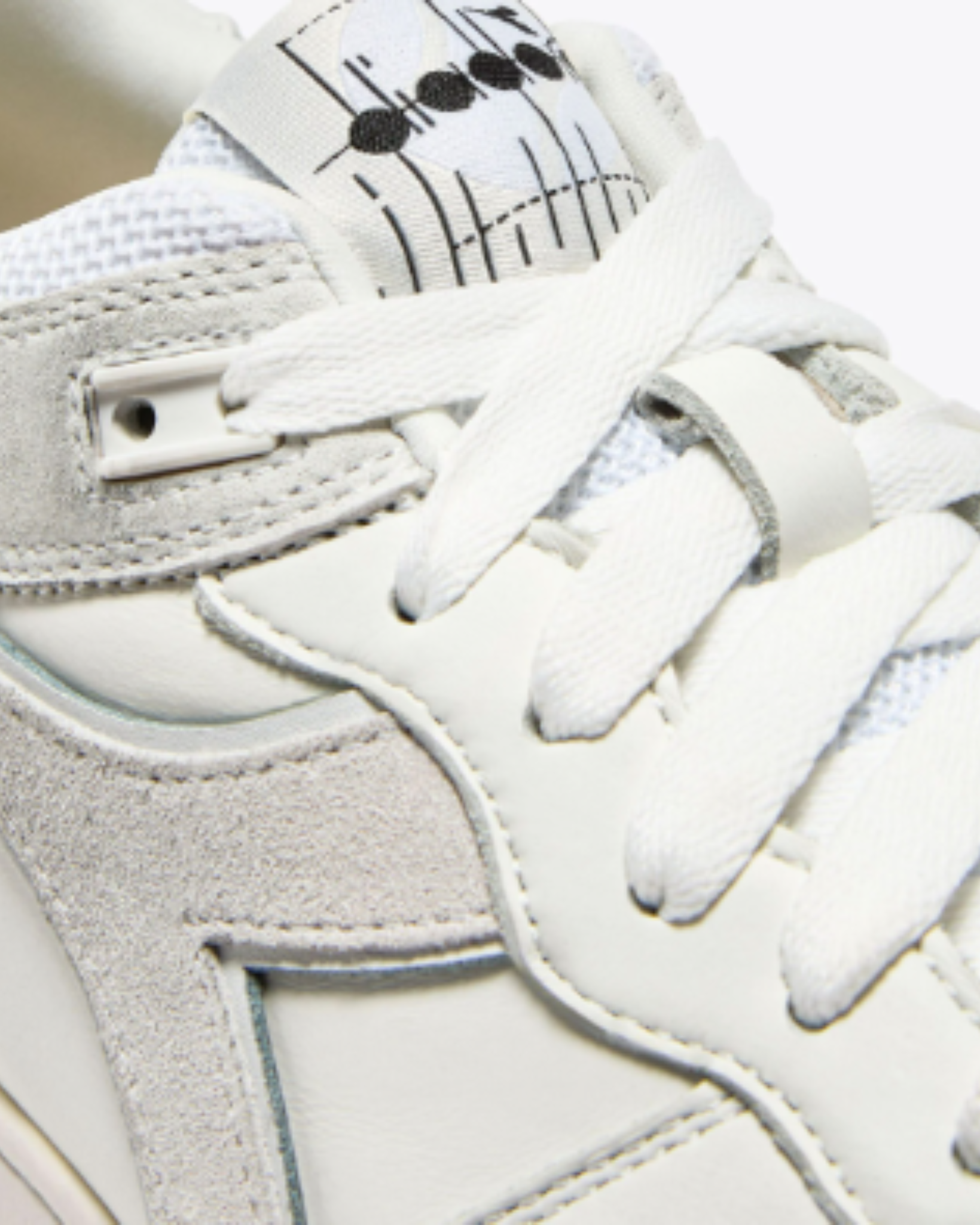 Diadora B. 560 USED - White shoe close-up showing textured tongue with retro logo print and suede panel stitching.