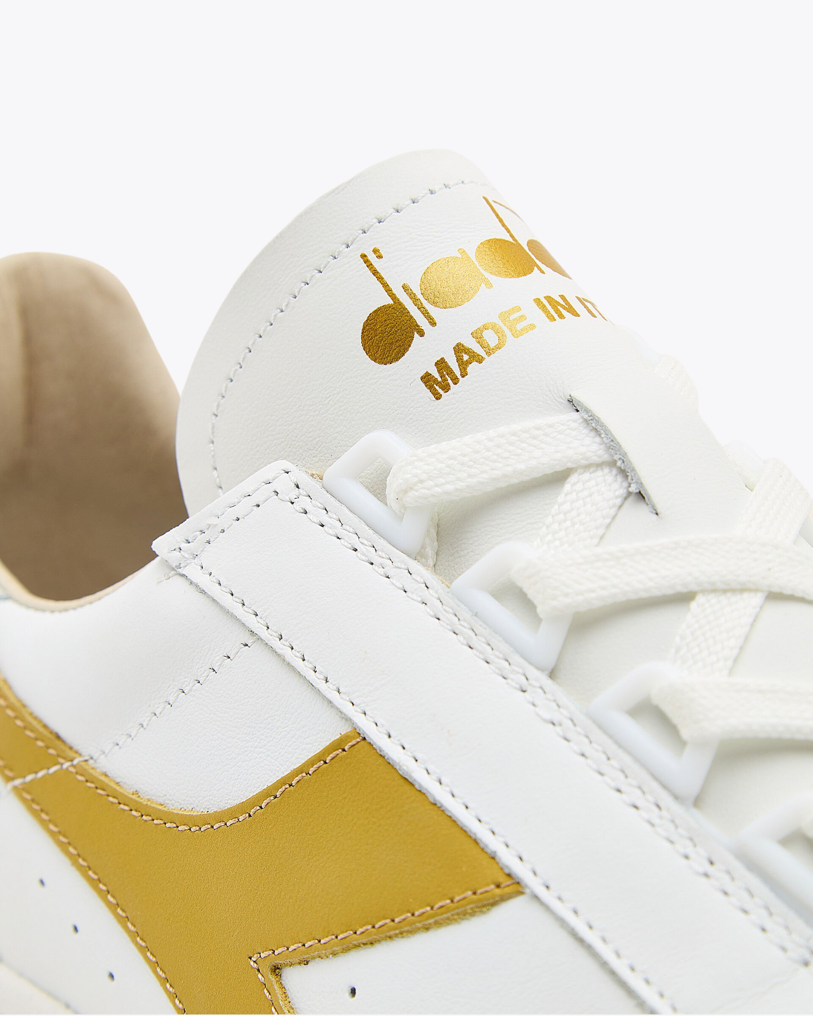 Diadora - B.Elite H Italia Sport - White / Gold shoe close-up of gold "Made in Italy" branding on tongue and side panel stitching detail.