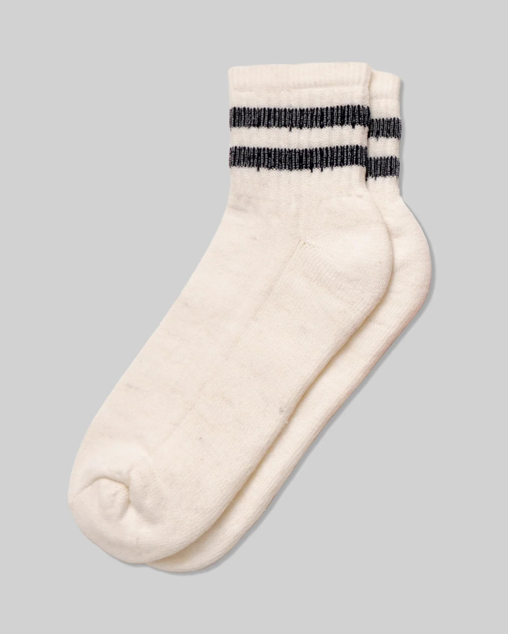 Merino Activity Quarter Natural with Navy laid flat in a top-down view with navy double stripe detailing around the cuff on a light grey background.