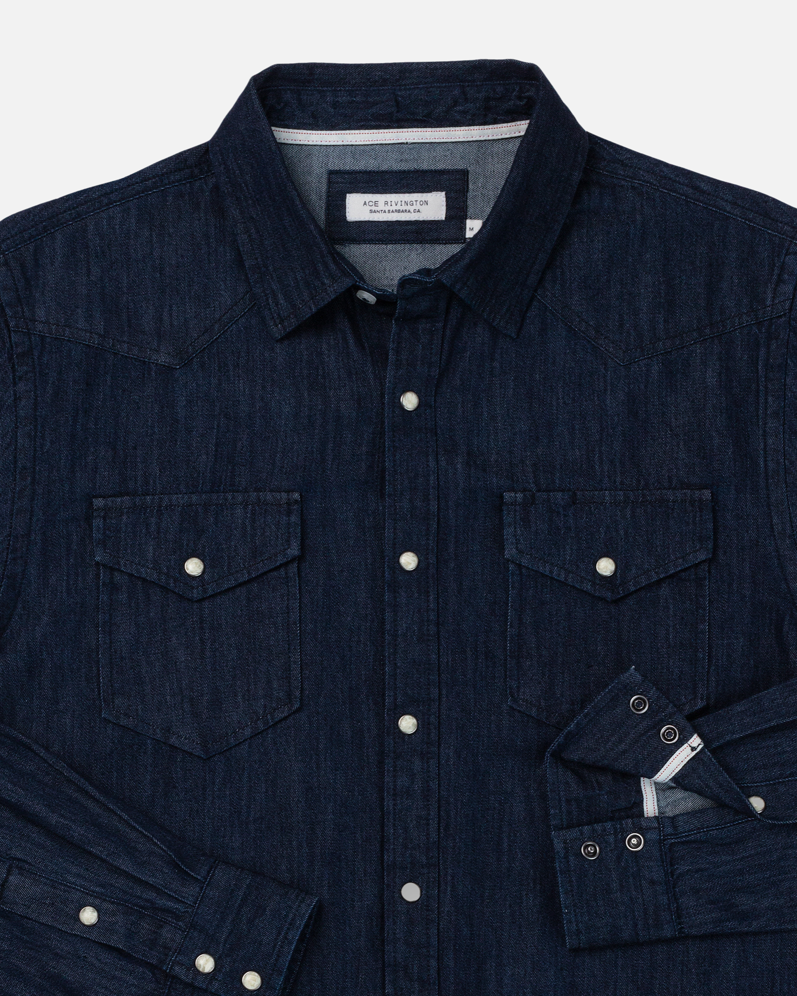 A dark wash mid-weight denim western H1 long-sleeve shirt by Ace Rivington. The shirt features a button-down front with metal snap buttons, two chest pockets with flap closures and snap buttons, and a classic collar. The cuffs are also fastened with snap buttons. The shirt has a rugged, stylish appearance suitable for casual wear.