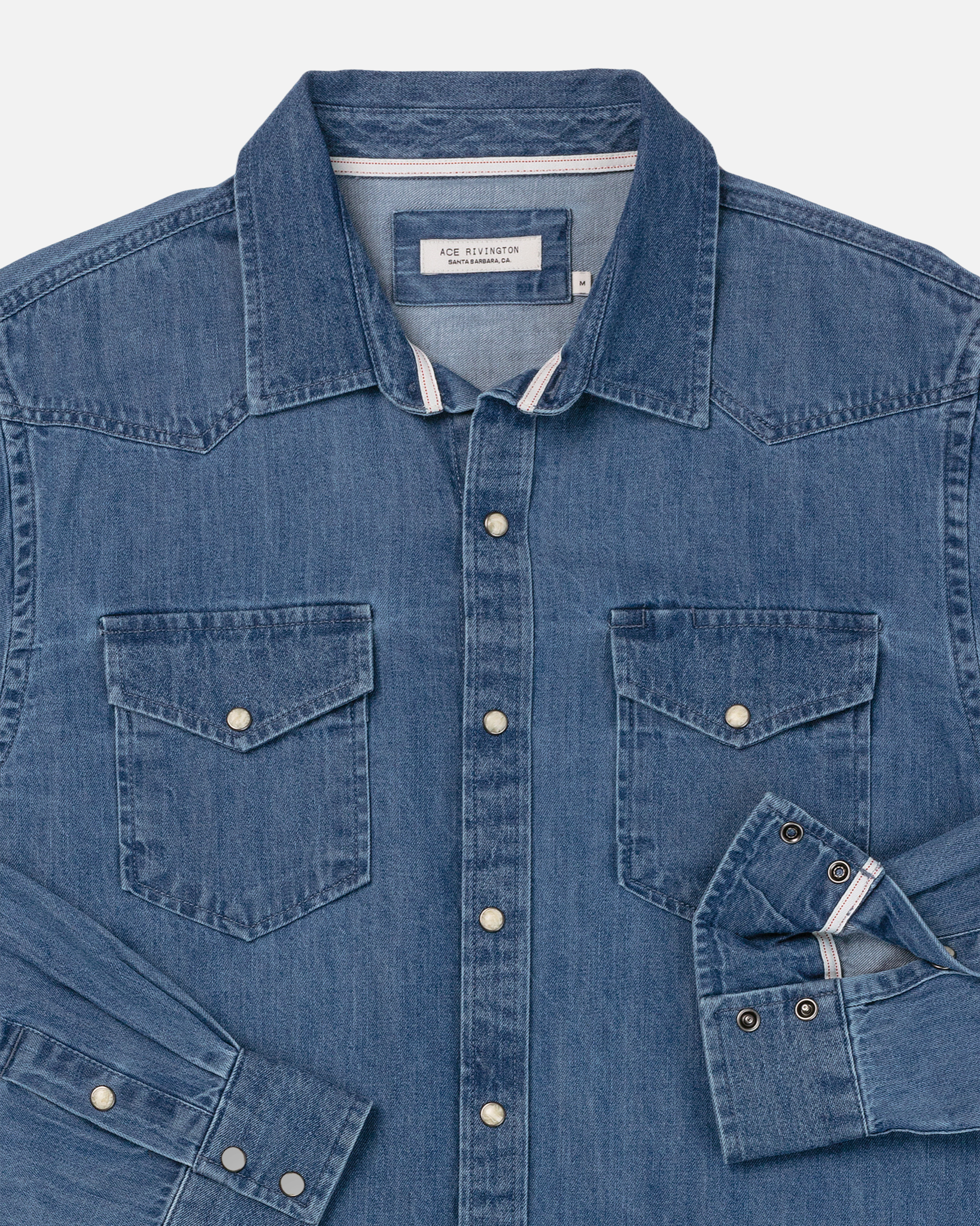 Ace Rivington Mid Weight Denim Western Shirt in Medium Wash. The shirt features a classic western design with two front chest pockets, each secured with a snap button. The shirt has a button-down front with snap buttons and a folded collar. The cuffs are also secured with snap buttons. The denim fabric has a medium wash, giving it a slightly worn-in look.