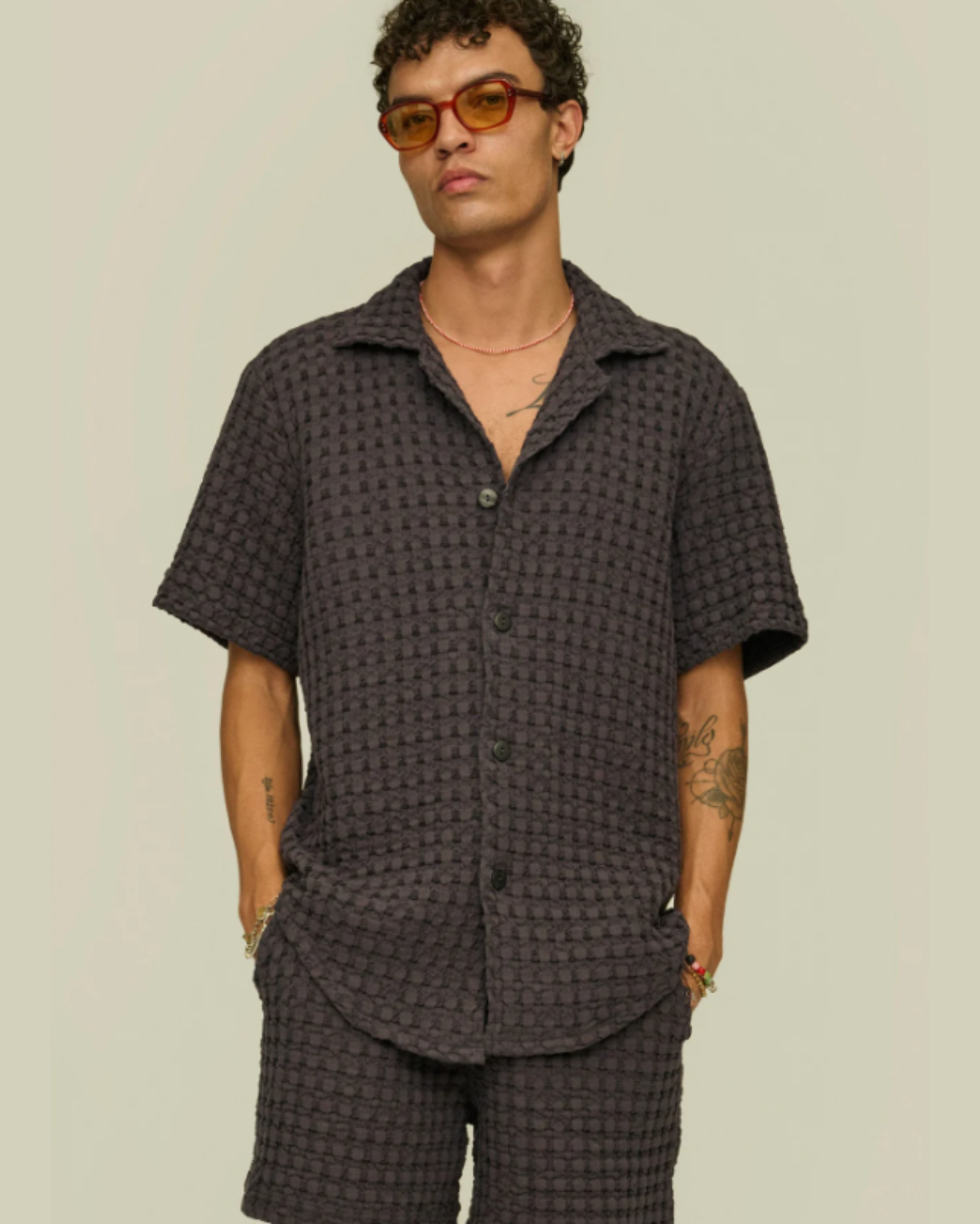 OAS Waffle - Cuba Shirt - Nearly Black worn by a male model in a relaxed pose with hands in pockets, showcasing the shirt's soft texture and casual drape with matching shorts.