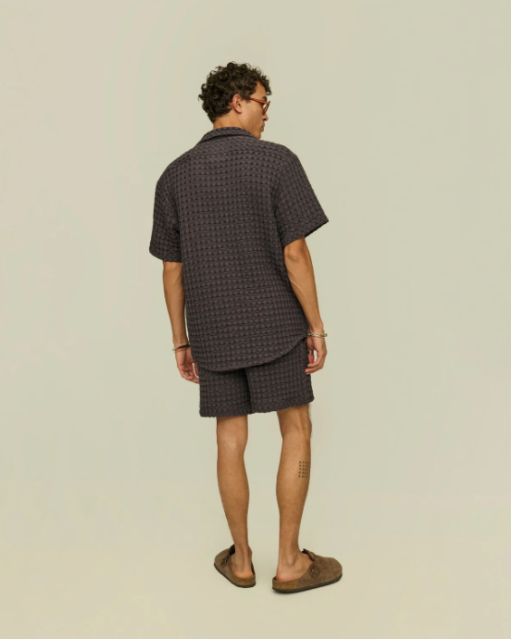 OAS Waffle - Cuba Shirt - Nearly Black shown from the back on a model, emphasizing the relaxed fit and curved hemline of the shirt in a tonal monochrome set.