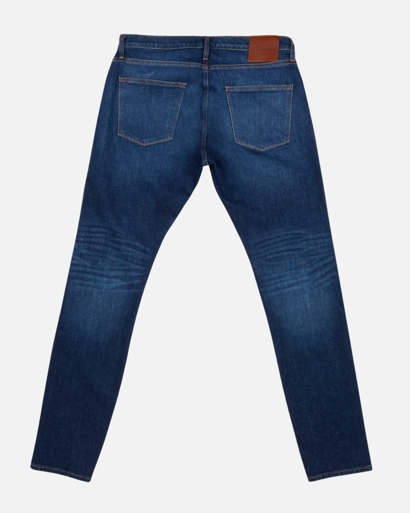fully extended back of pair of high quality slim cut men's dark blue jeans with slight wear