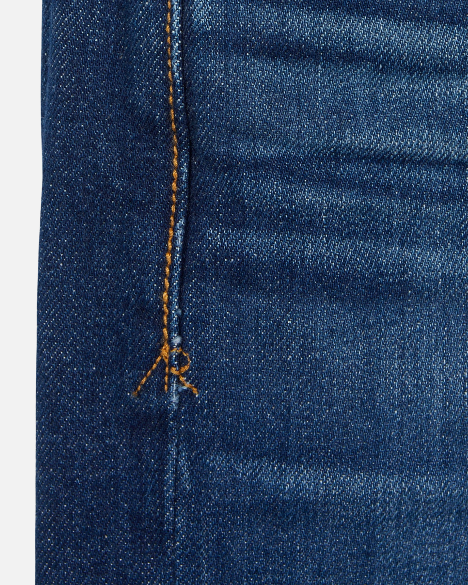 close up of stitching of pair of high quality slim cut men's dark blue jeans with slight wear
