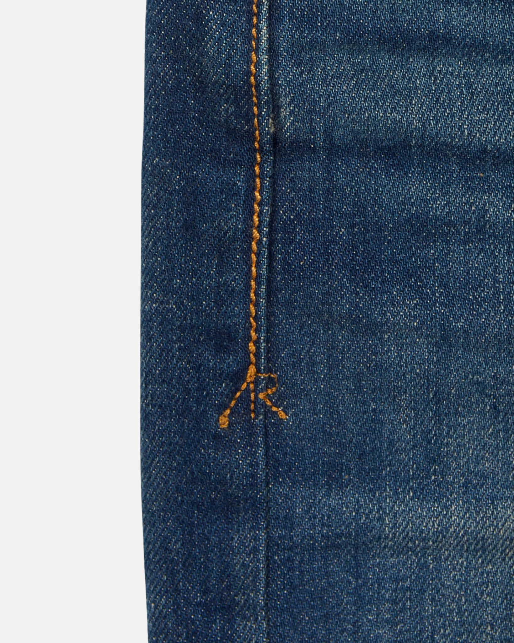 close up of stitching of pair of high quality slim cut men's green hue blue jeans with slight wear