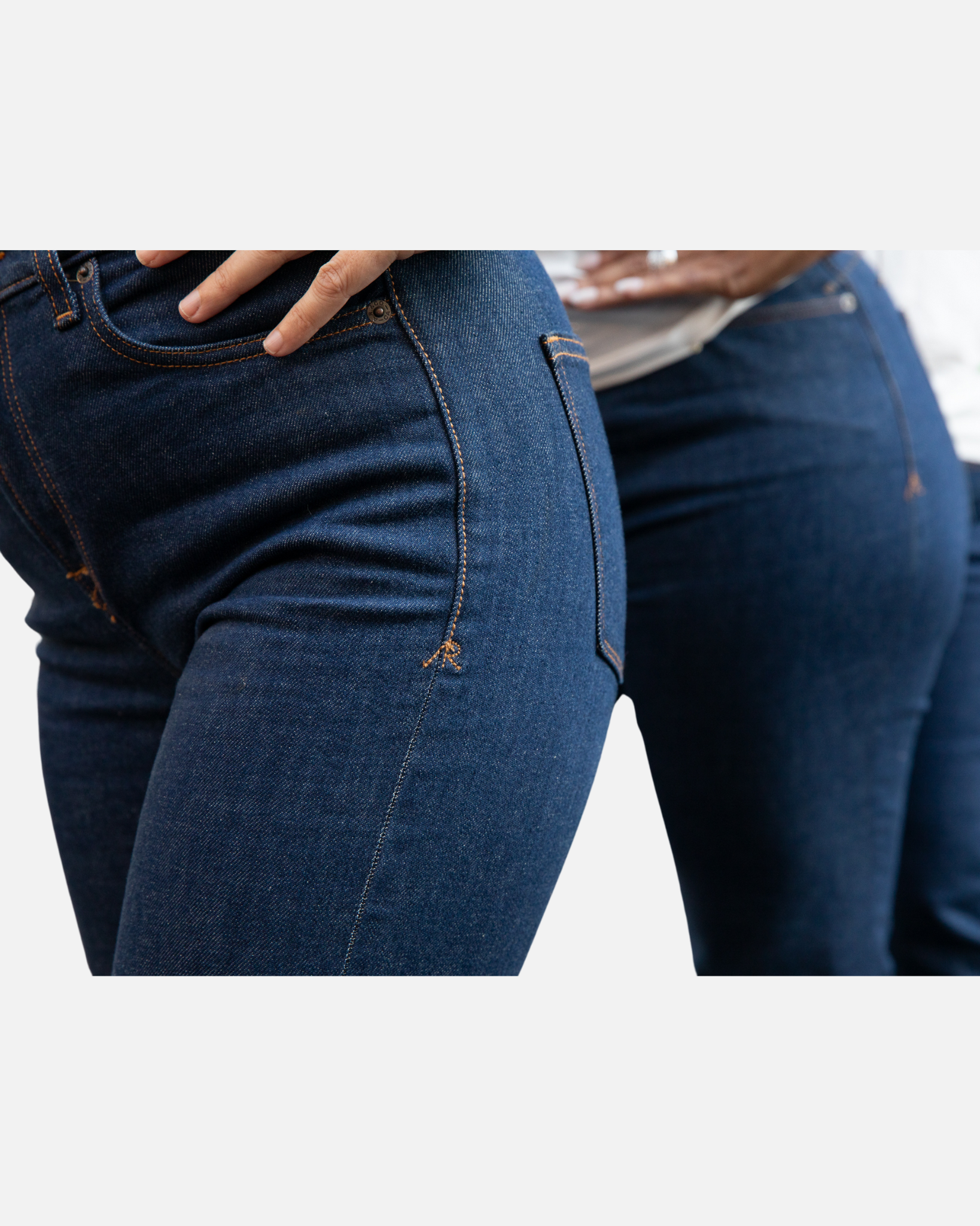 Close-up view of two individuals wearing Ace Rivington Women's Classic Straight Comfort Denim Jeans - Dark Rinse focuses on the fit and texture of the jeans, highlighting the dark blue color, stitching details, and the snug fit around the hips and thighs. The individuals are standing side by side, showcasing the jeans from different angles.