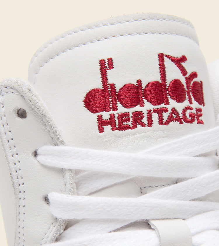 front angled view of red lettering on the lip of diadora white mi basket used shoe with red stripe