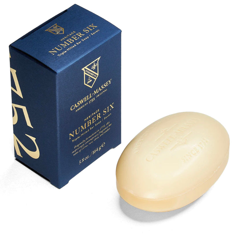 Ace Rivington Caswell-Massey Heritage Number Six soap zoom-in as the same first image shows a blue box with gold lettering and a matching oval-shaped soap bar. The box is labeled 'Caswell-Massey Heritage Number Six Triple-Milled Bar Soap Since 1752.' The soap bar is embossed with similar branding.