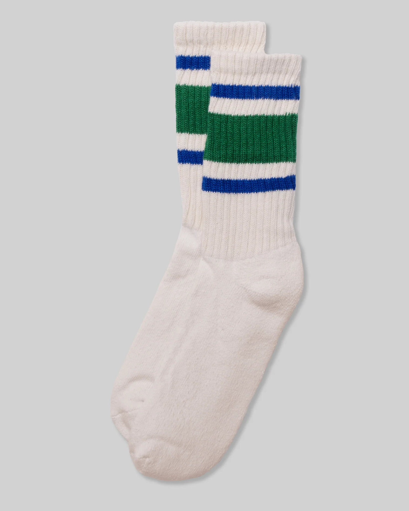 American Trench Retro Stripe Socks in Green, Blue, and White are displayed in a flat lay, featuring wide green and blue stripes on a light grey background. This design evokes vintage athletic socks, adding a stylish and nostalgic touch.