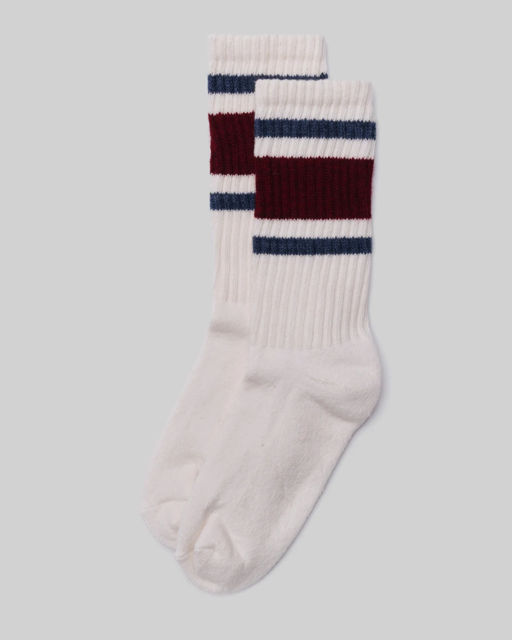 American Trench Retro Stripe Socks in maroon, navy, and white lay flat in a stacked position, featuring maroon and navy stripes on a light grey background. This design evokes vintage athletic socks, adding a nostalgic and stylish touch.