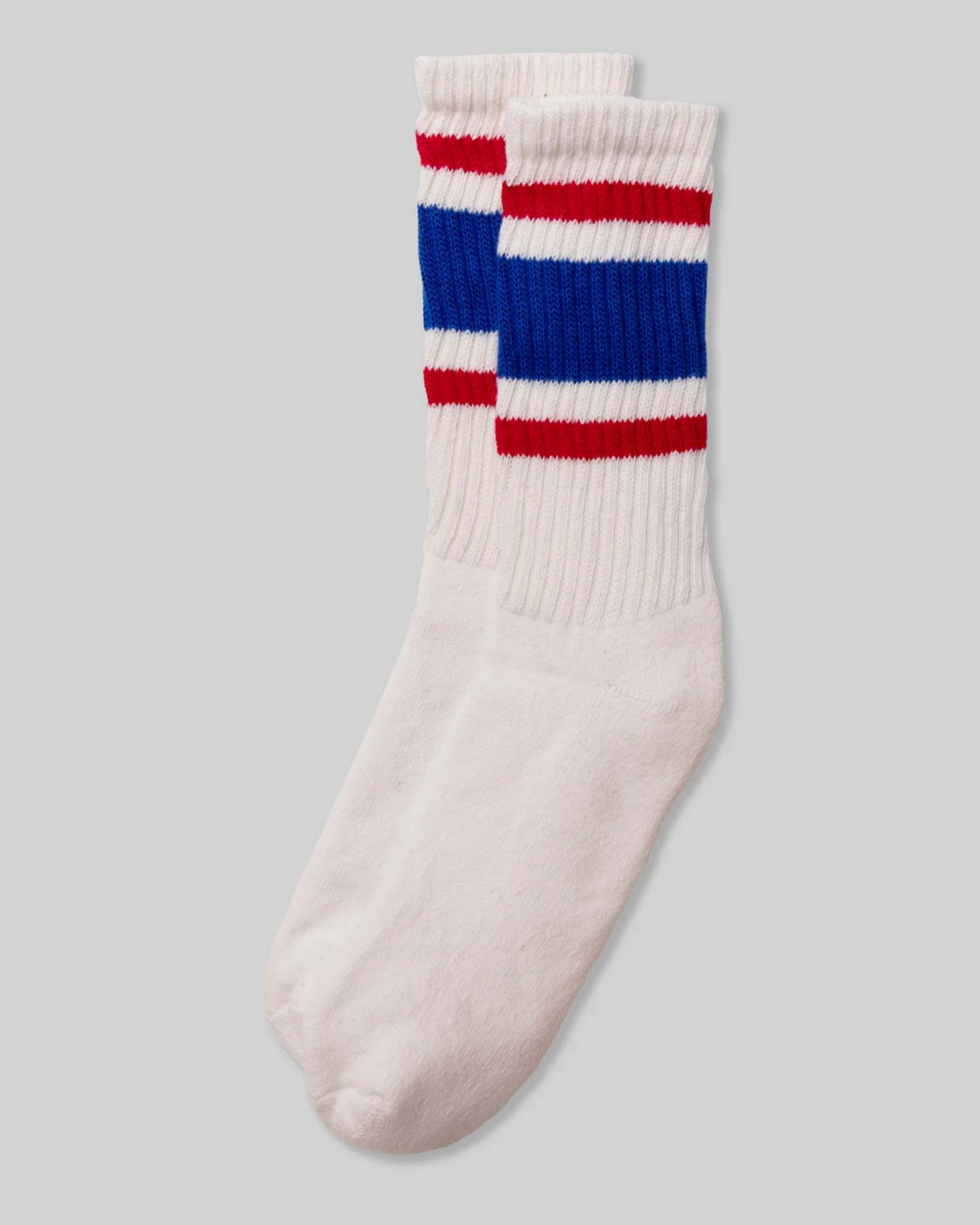 American Trench Retro Stripe Socks in red, blue, and white are laid flat from a top-down view, showcasing a stacked design with vibrant red and blue cuff stripes. The design evokes vintage athletic socks, providing a nostalgic yet stylish touch.