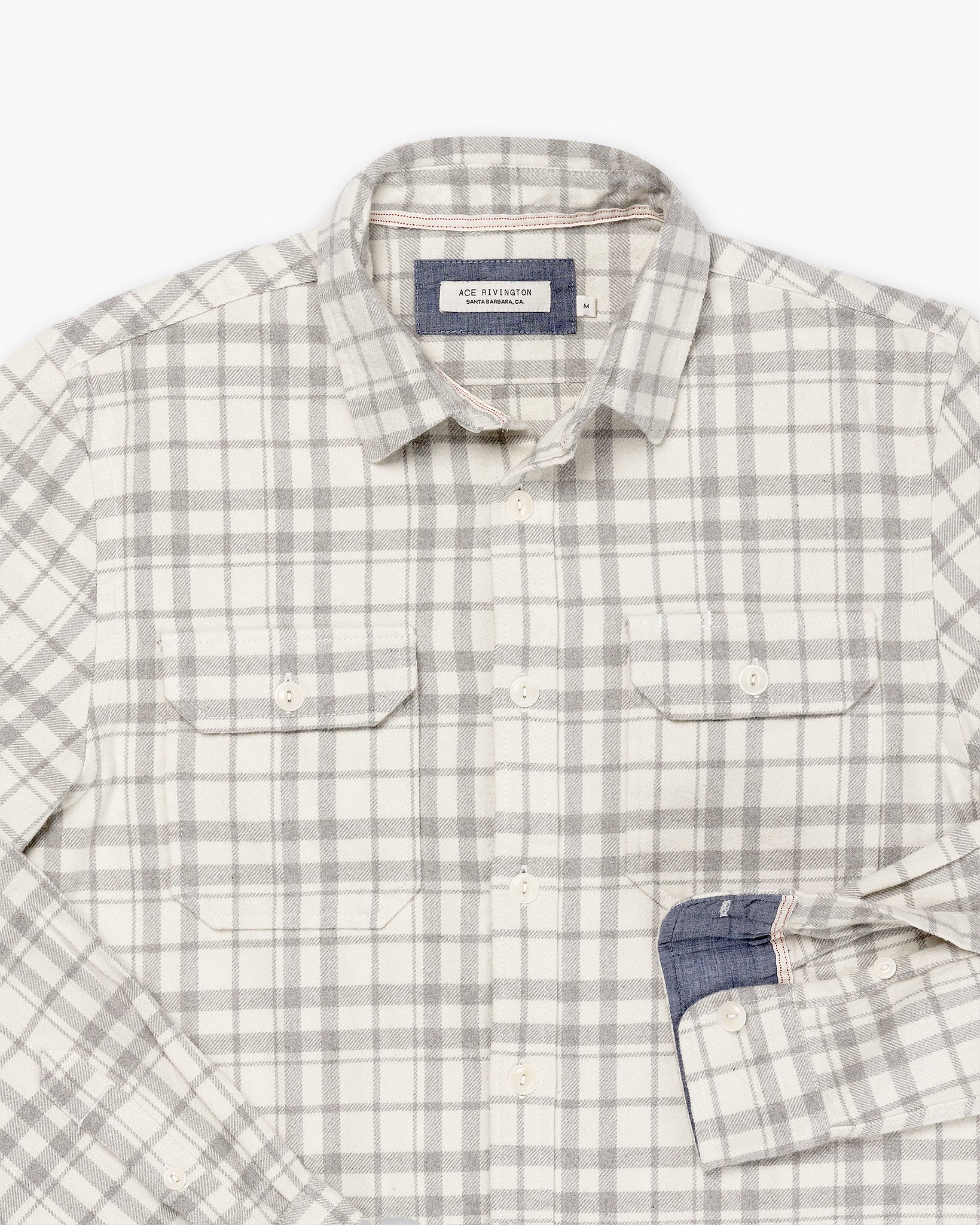 close up of cuff and breast pocket of men's off white and grey winter flannel shirt