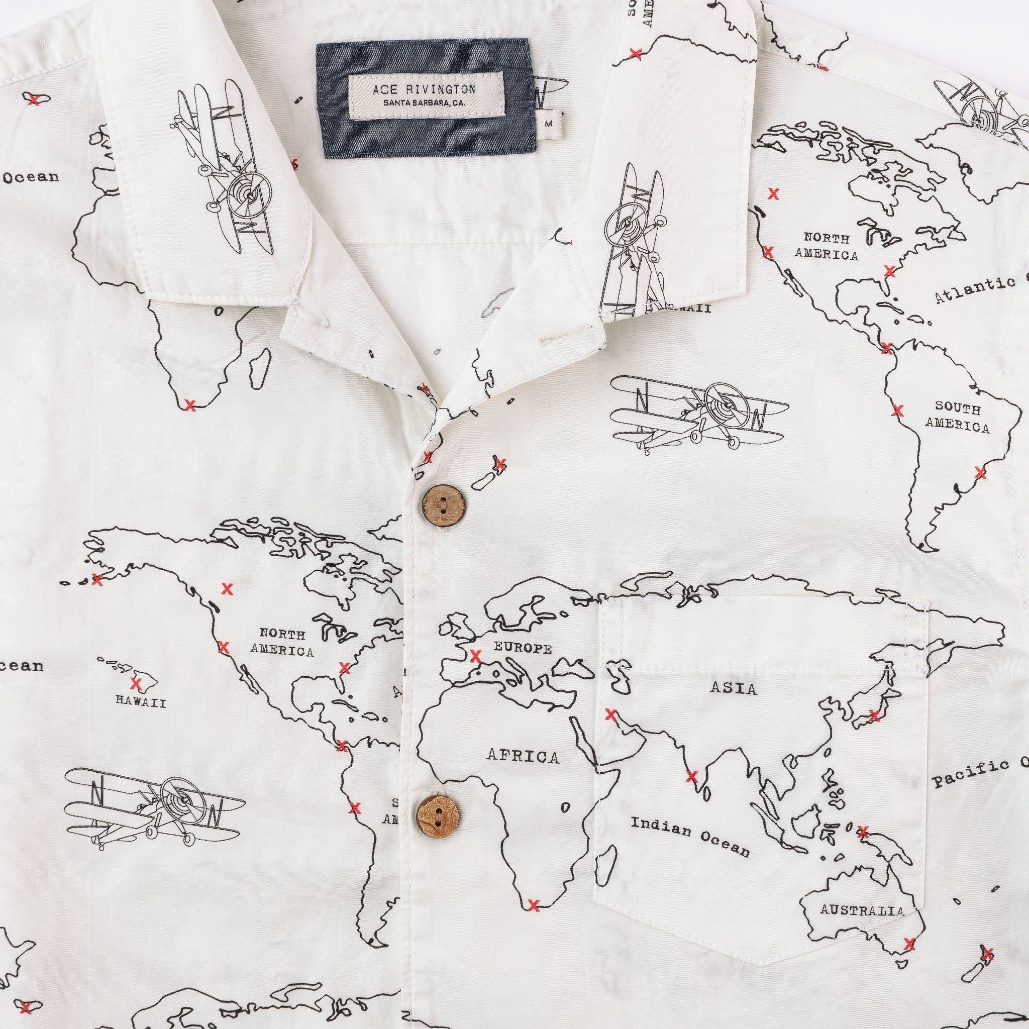 close up of tag, buttons, and pocket on front of men's map print short sleeve button up shirt with wooden buttons