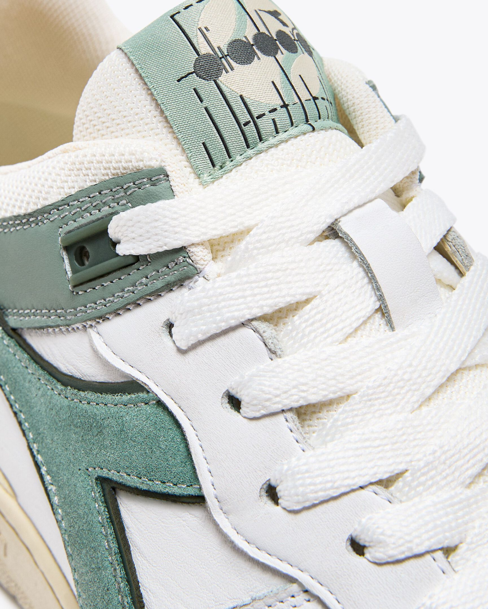 Diadora B. 560 USED - Iceberg Green shoe close-up of tongue logo and textured lace panel with green leather overlay.