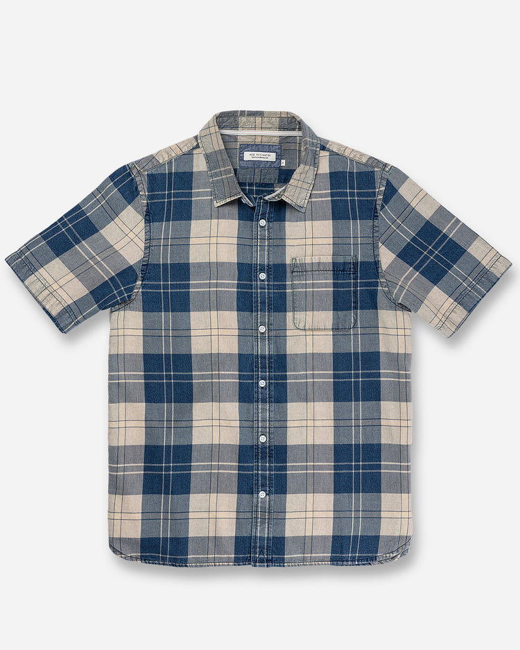 Front of full-view flat lay of Ace Rivington collared short-sleeved tailored 100% cotton shirt with real indigo slight blue and beige plaid patterning and left breast pocket 
