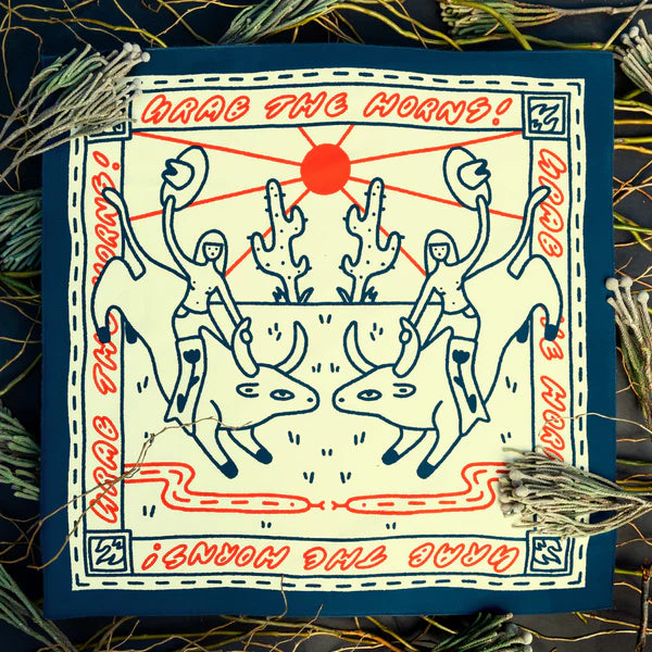 The Grab The Horns - Bandits Bandana by Ace Rivington features a cream background with a dark blue border. It shows two figures riding bulls, each holding a hat and gripping the bull's horn against a desert scene with cacti and a red sun. The phrase "GRAB THE HORNS!" is repeated in red along the border, framed by a stitched pattern and decorative twine and foliage, enhancing its rustic theme.