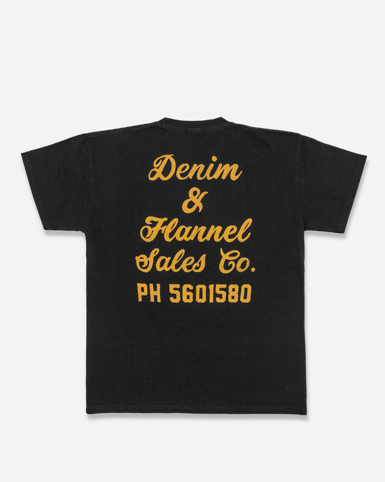 back of men's black graphic tee with gold lettering reading "denim & flannel sales co. ph 5601580"