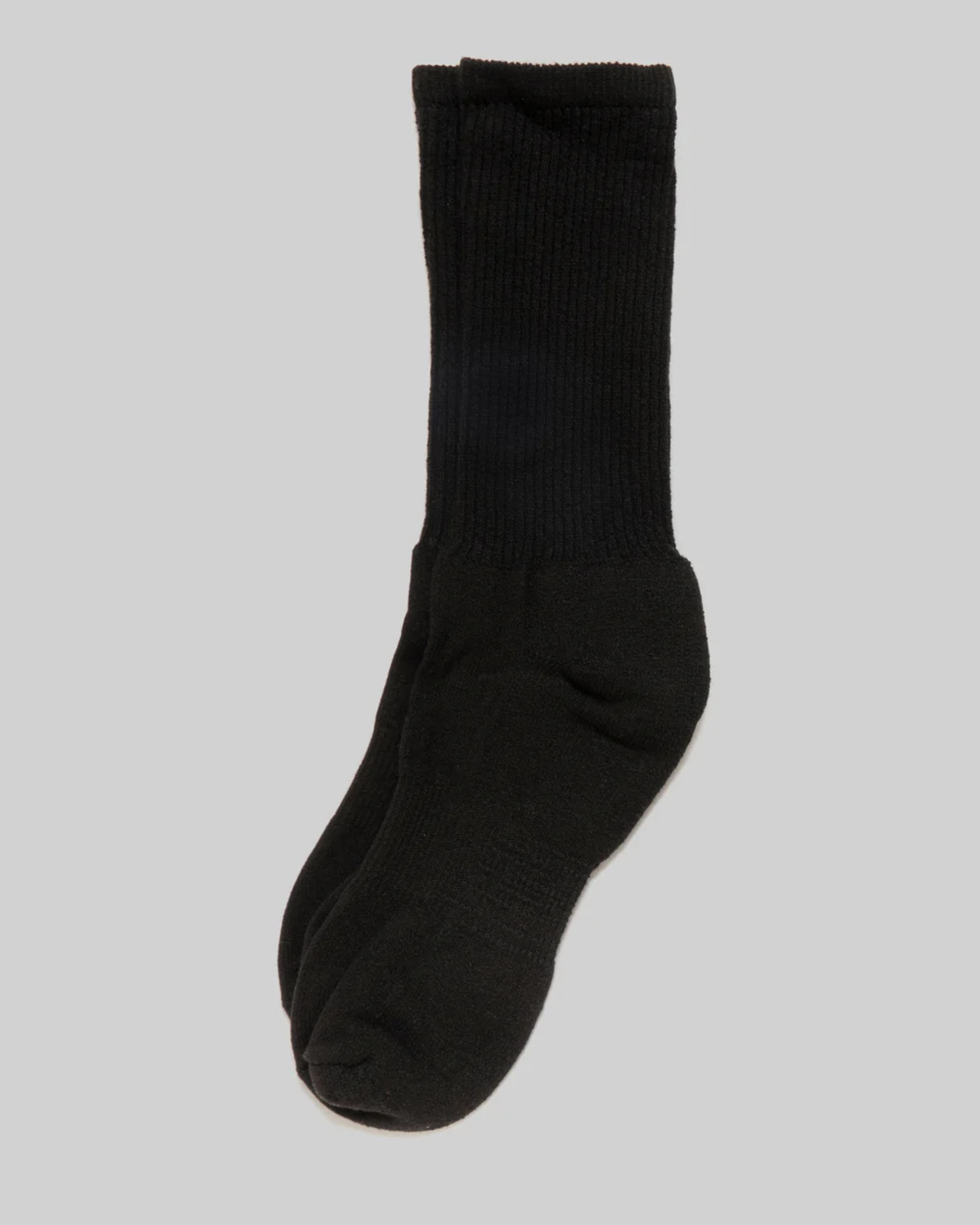 Mil-Spec Sport Sock - Black in a top-down view, laid flat against a light grey background. These mid-calf length socks feature a ribbed cuff and a cushioned body. The upper portion has a ribbed texture, while the foot area has a smooth finish. This design emphasizes the durability and functional style of the socks, making them suitable for various physical activities.