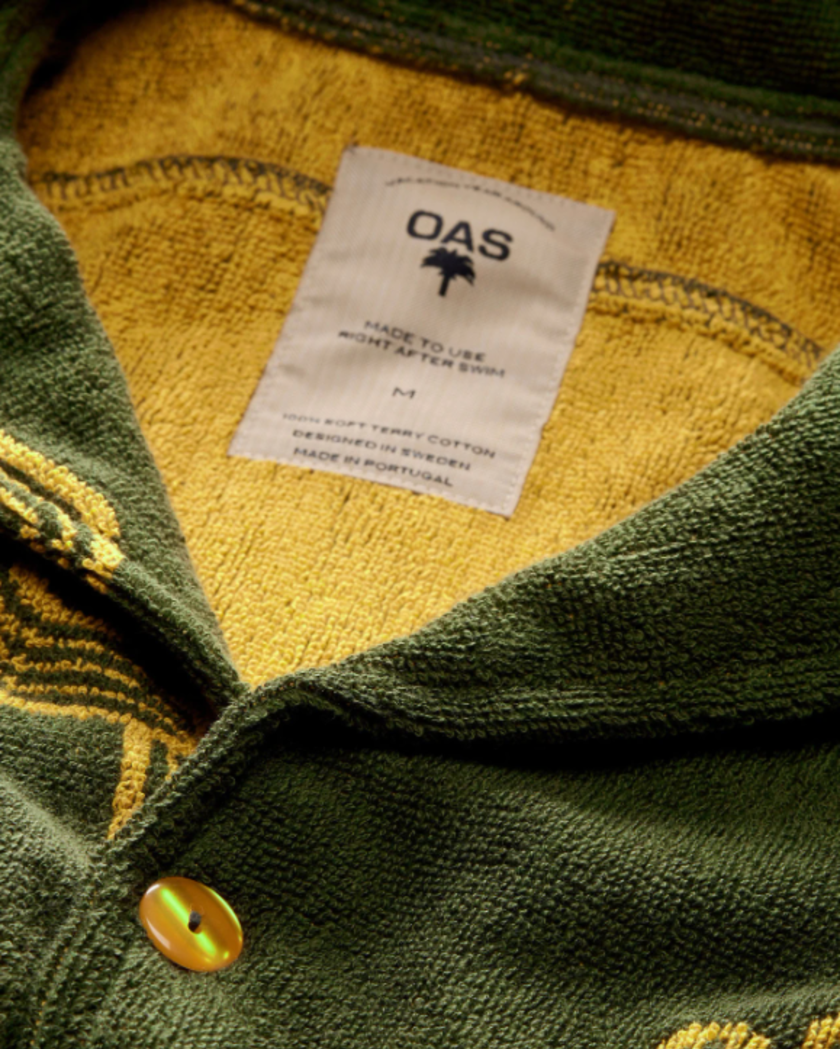 OAS Terry - Cuba Shirt - Mezcal close-up of the inner label and textured terry cloth fabric, showcasing the vibrant yellow interior and embroidered detailing on the collar.