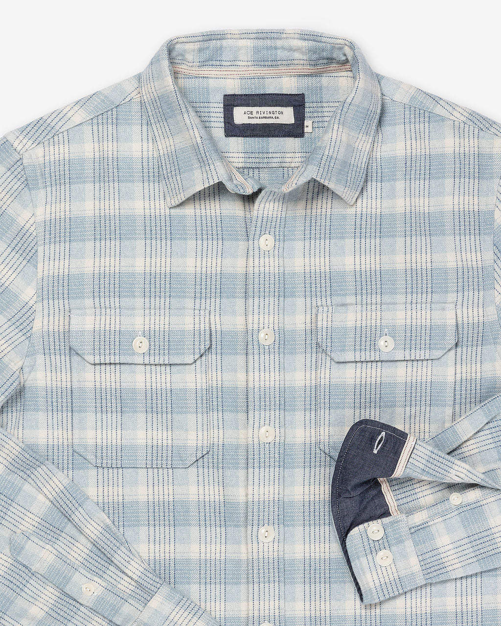 Zoomed-in details of the inside of sleeve, tag, buttons, collar, and breast pockets on Ace Rivington soft-brushed flannel shirt with pearl buttons and off-white and light blue and black checkered grid plaid design with pearl buttons and double breast pockets with buttoned enclosure