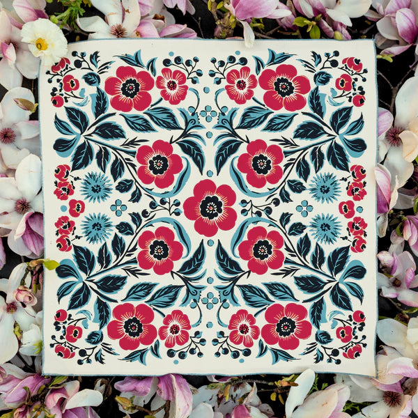 The Ace Rivington Bandits Bandana - Spring Awakening features a white background with large red flowers, black centers, and blue accents, surrounded by intricate black and blue leaves and smaller blue flowers. The border includes smaller red and blue flowers, enhancing the spring theme.