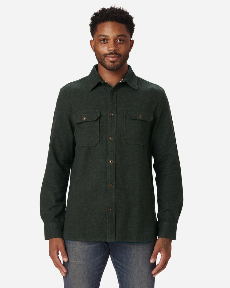 Model facing directly forward wearing Ace Rivington men's forest green flannel with brown buttons and a white collar stripe