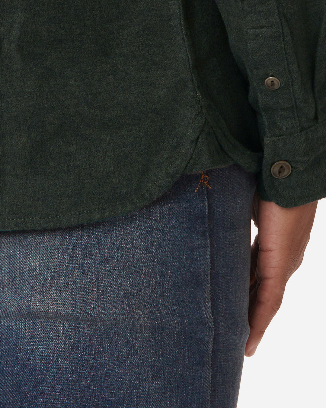Signature "AR" stitching and bottom flannel hem on model wearing Ace Rivington men's forest green flannel with brown buttons and a white collar stripe and Ace Rivington dirty vintage blue denim jeans