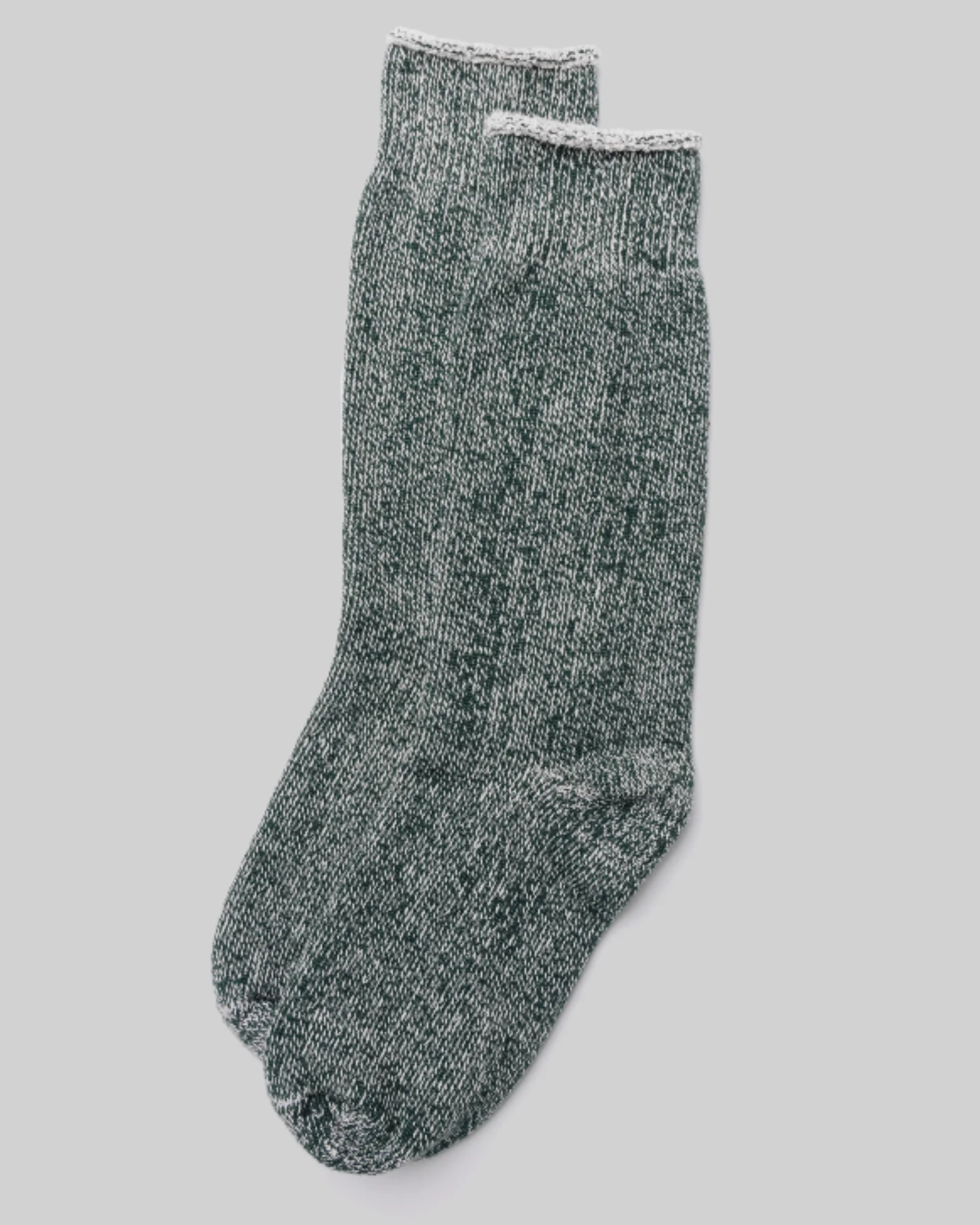 The Sunday Sock - Bottle Green features a top-down view, laid flat, showcasing a marled green and white knit with a rolled cuff on a light grey background. Its comfortable and warm design makes it perfect for casual or lounging wear.