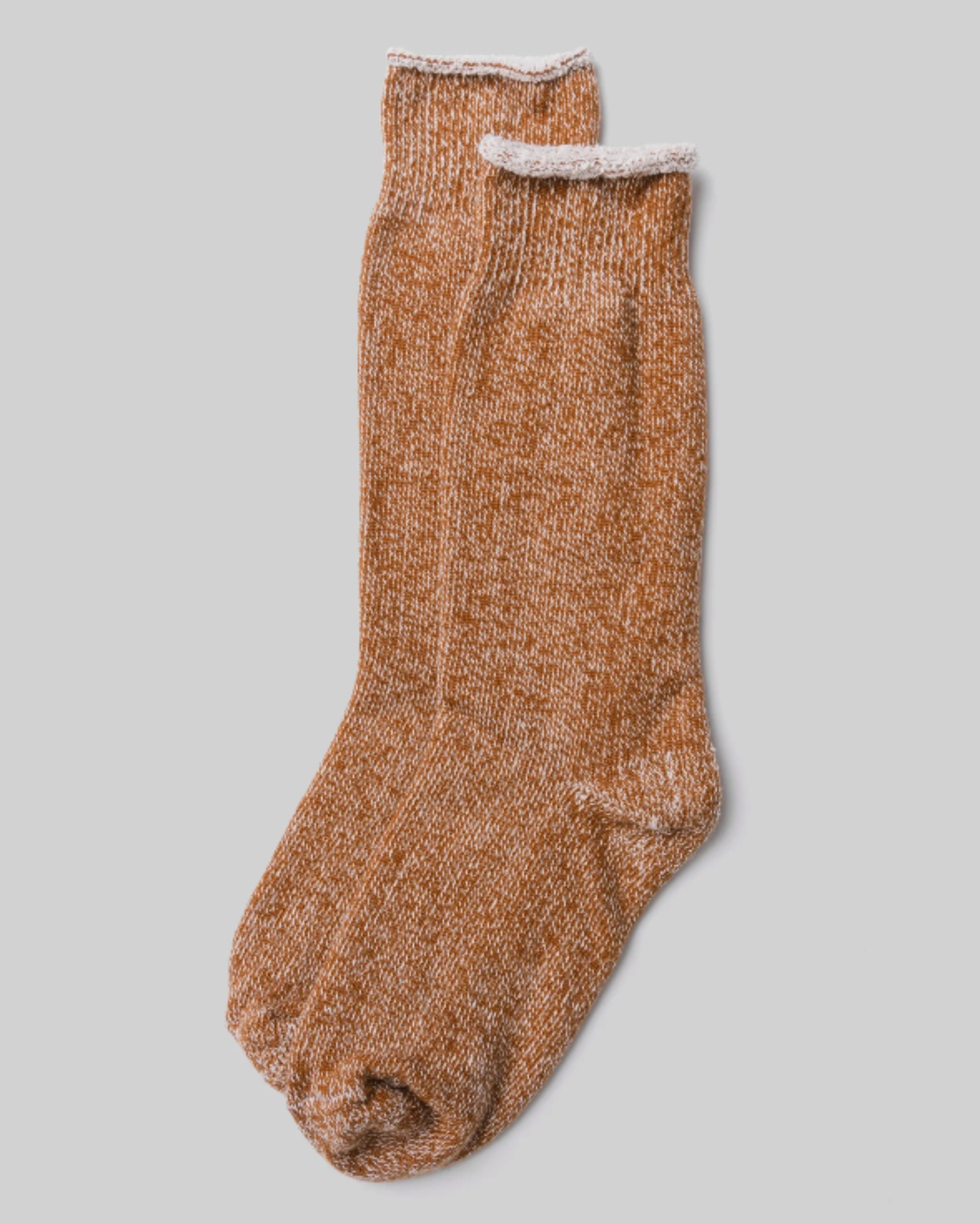 The Sunday Sock - Mustard in a top-down view, showcasing a marled mustard and white knit design with a rolled cuff against a light grey background. This sock features a comfortable and plush design that combines the softness of a sock with the cozy feel of a slipper.