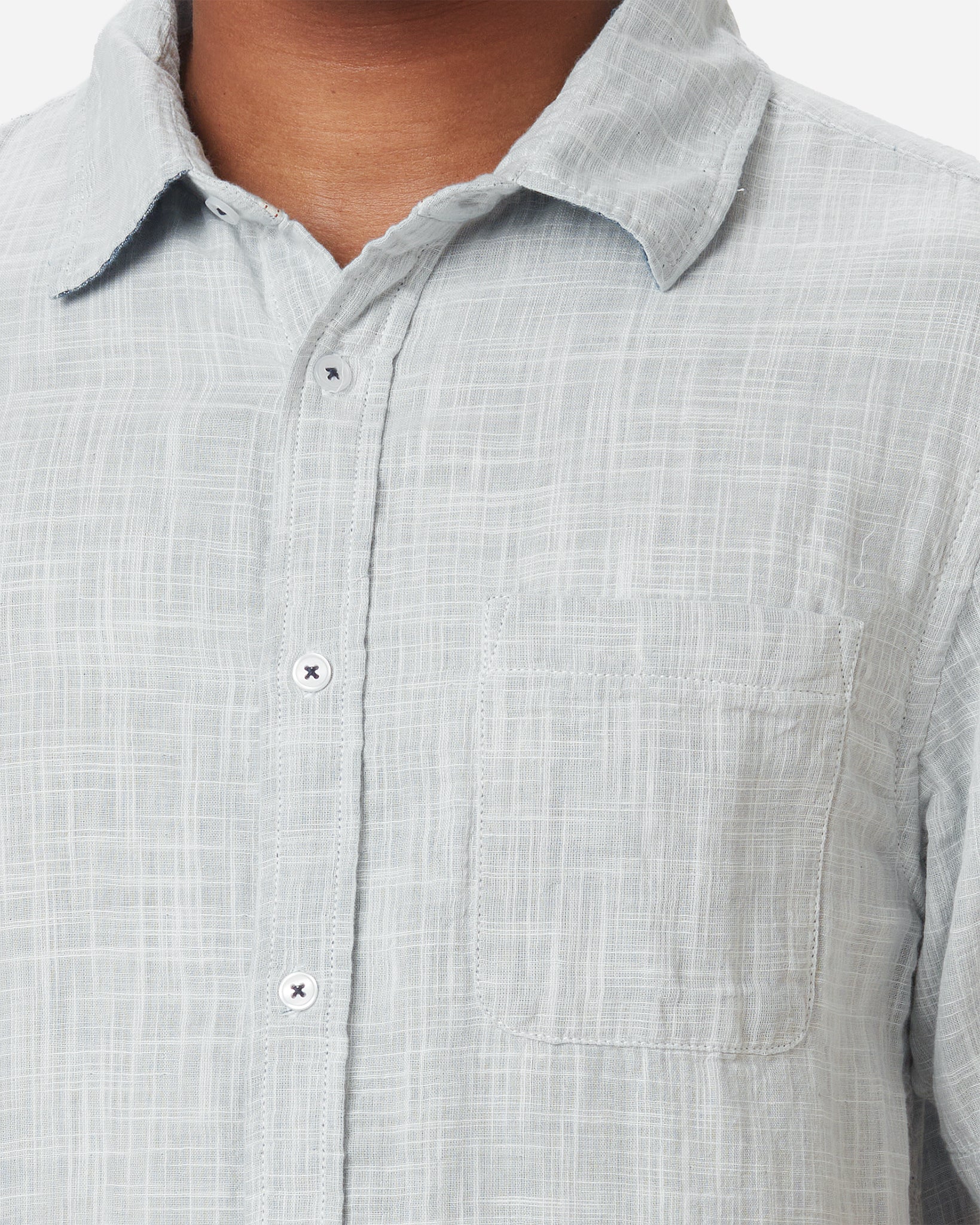 Zoom in of neck, collar, breast pocket, and buttons on model wearing Ace Rivington collared grey short-sleeved double gauze soft-textured cotton shirt with indigo blue interior, pearl buttons, and left-breast pocket 