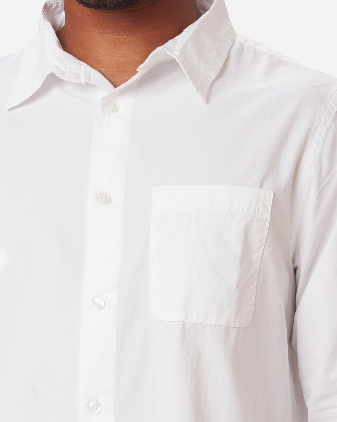 detail of breast pocket, neck, and collar on model wearing men's white long sleeve tailored poplin shirt with color matched buttons and a single pocket in standard height option