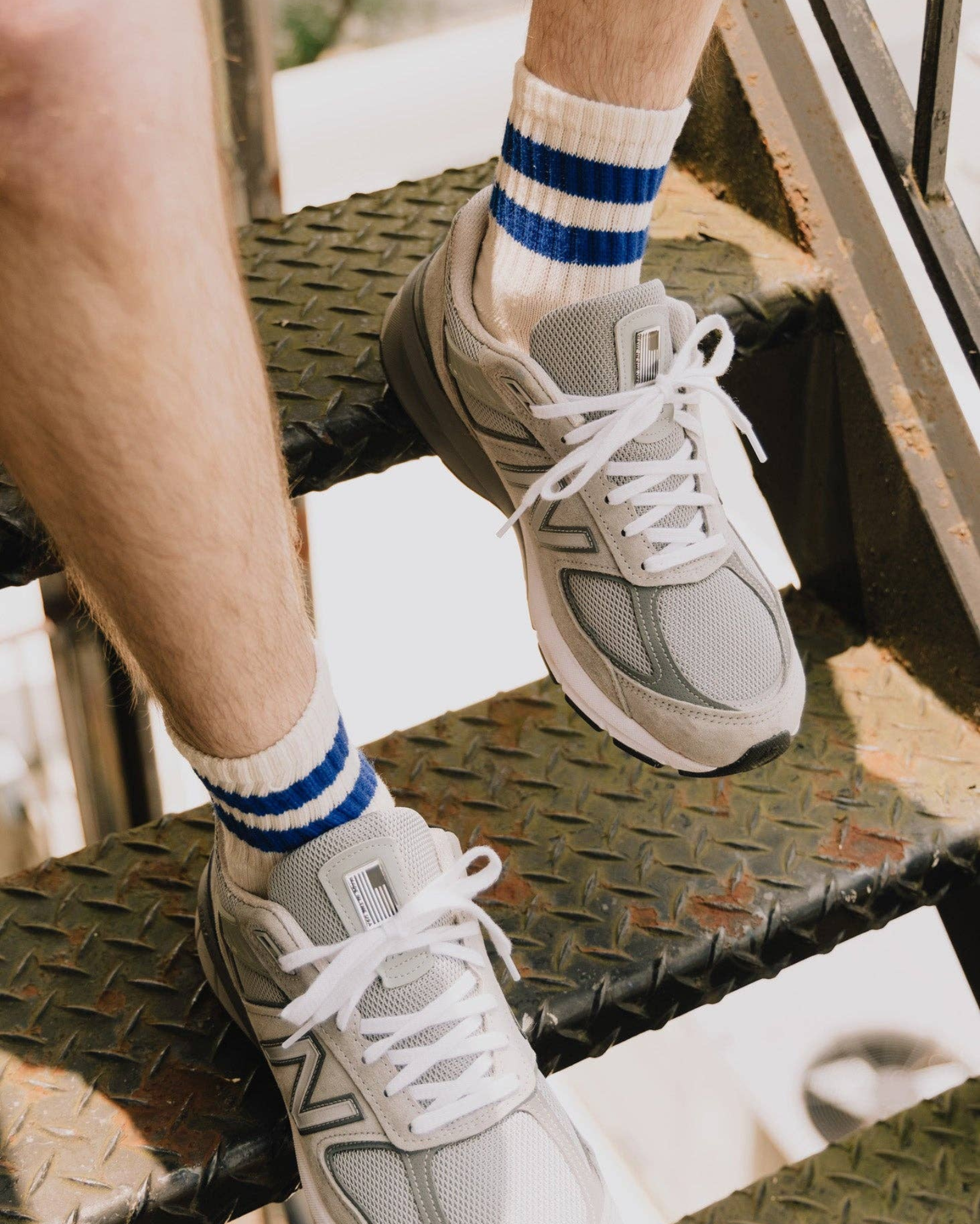 The Mono Stripe Quarter Crew – Royal Blue: Lifestyle image showing The Mono Stripe Quarter Crew in royal blue stripes worn with gray mesh shoes on a metal staircase.