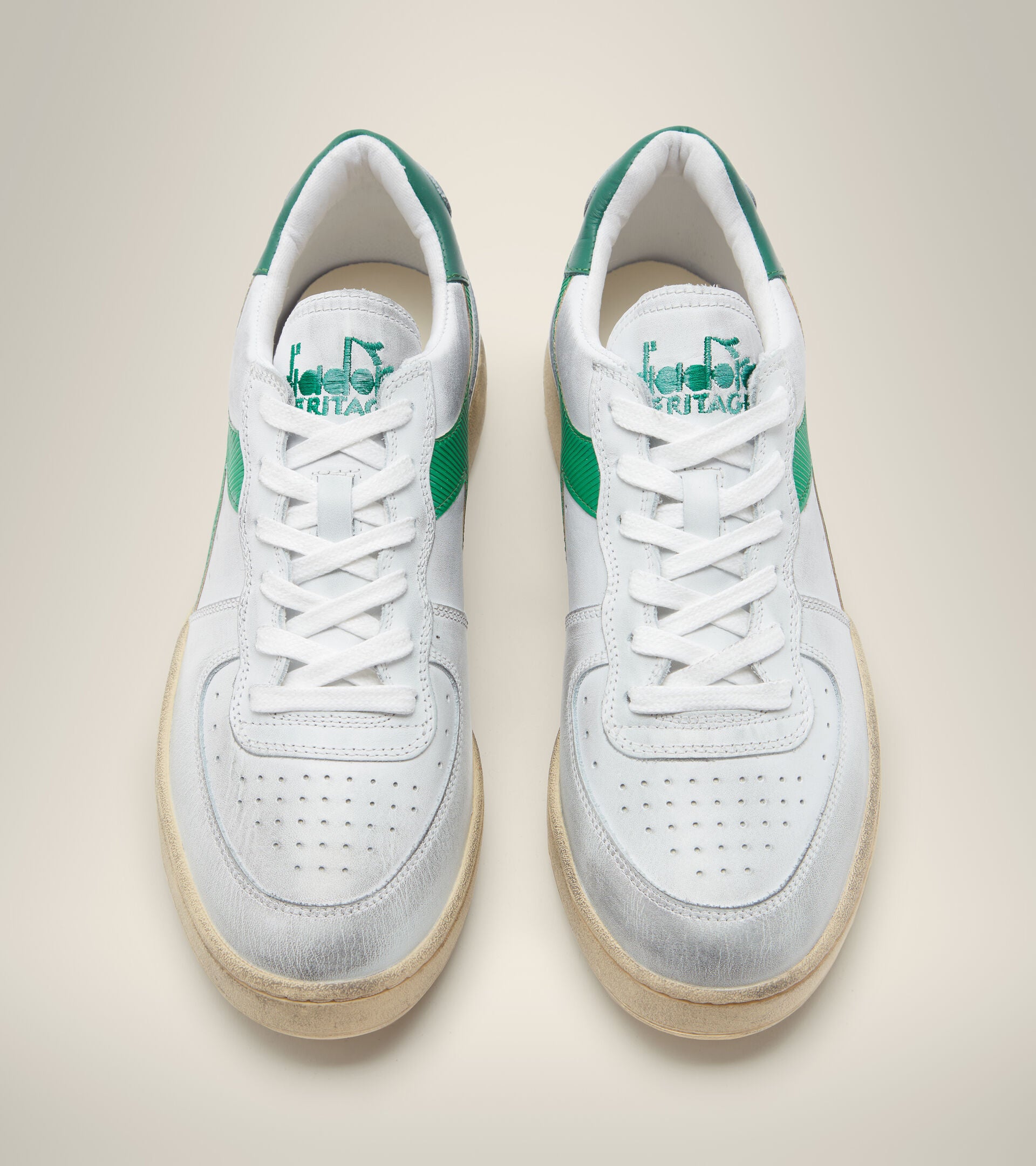 side by side aerial view from above of white diadora men's mi basket low used shoes with a light green stripe