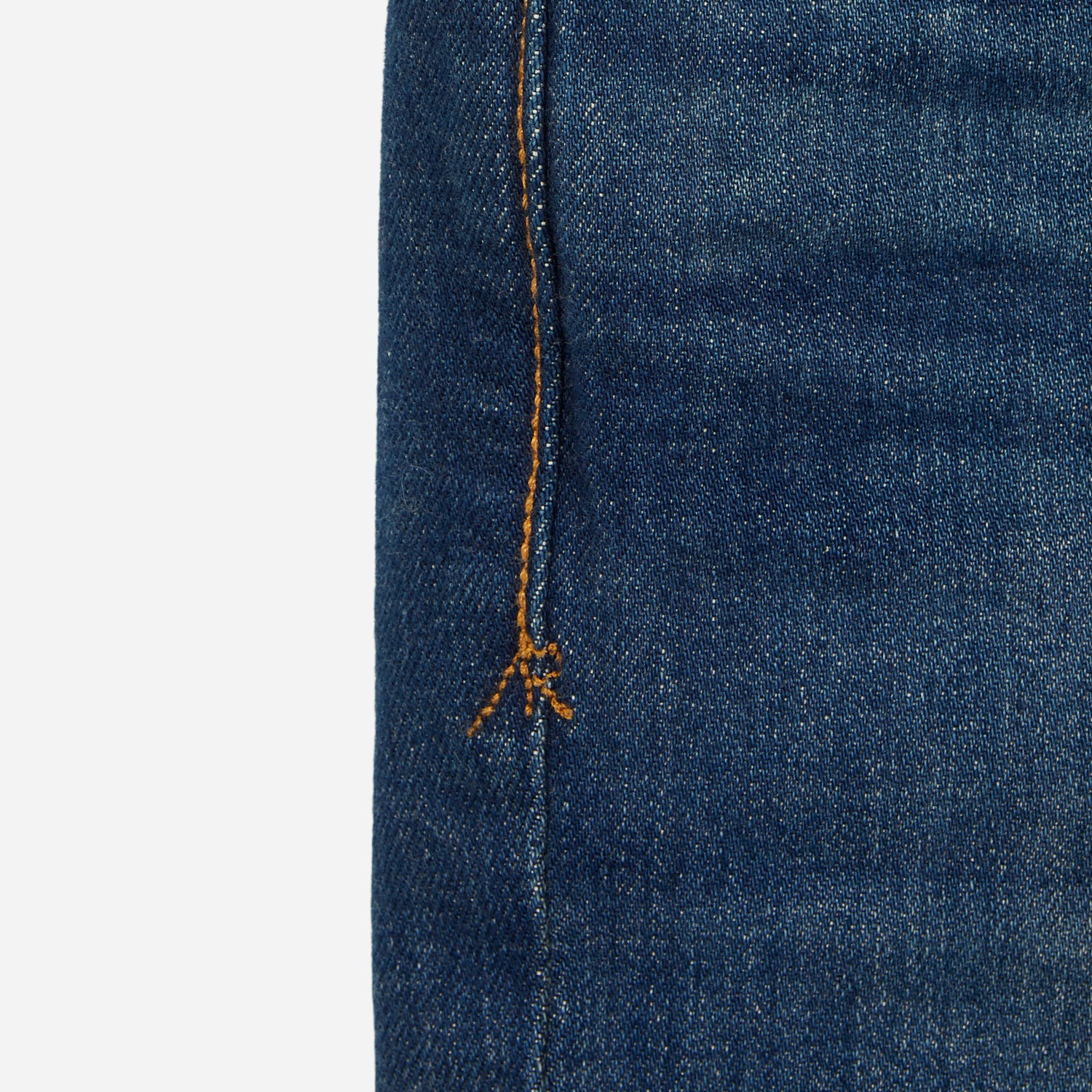 close up of stitching on pair of men's athletic taper blue jeans with slight wear 