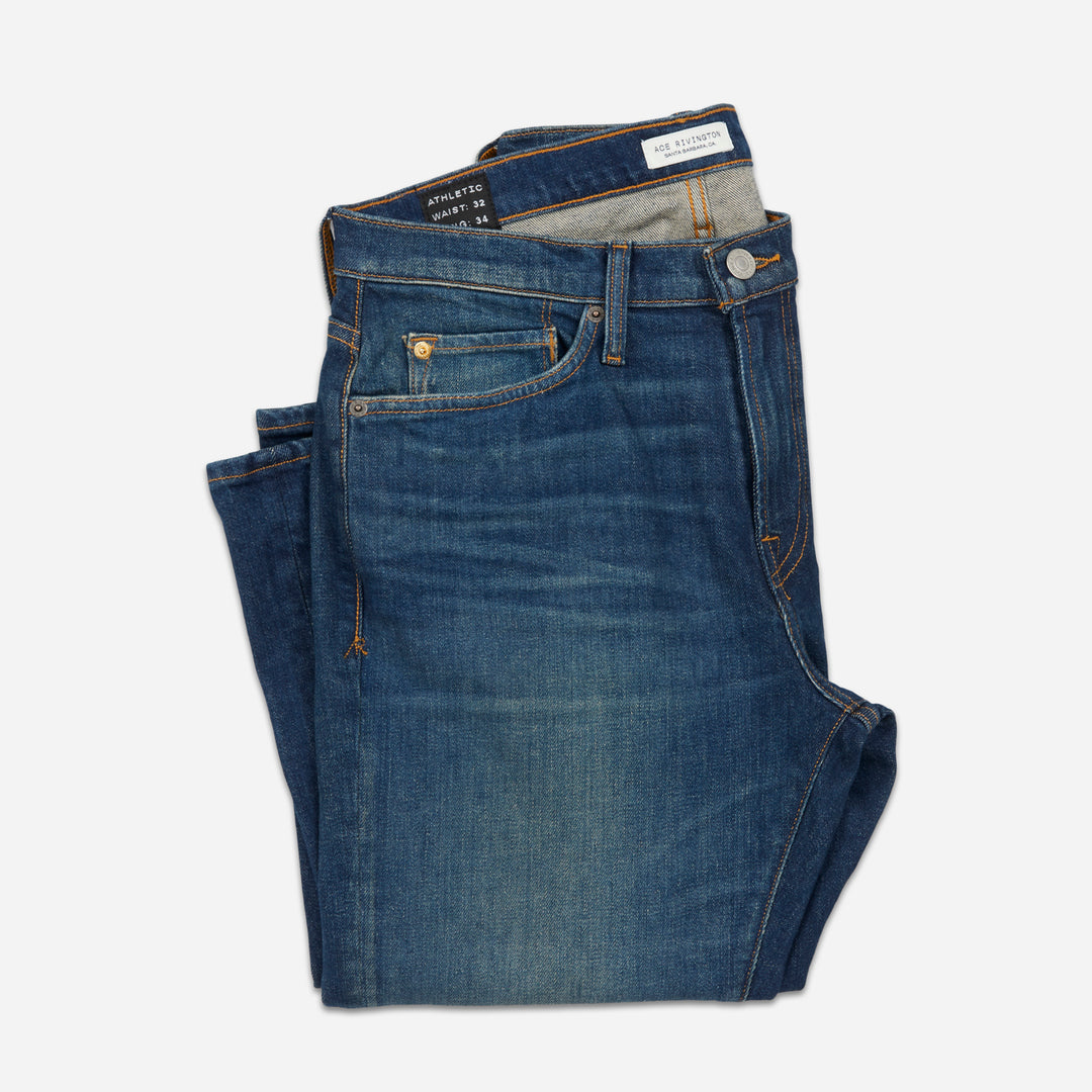 folded pair of men's athletic taper blue jeans with slight wear 