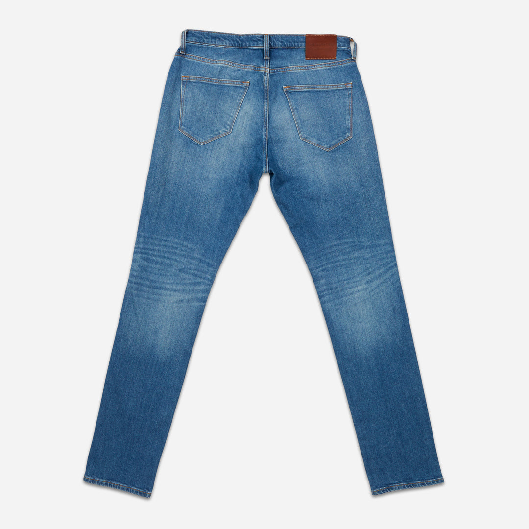 back of folded pair of men's athletic taper medium light blue jeans with slight wear 