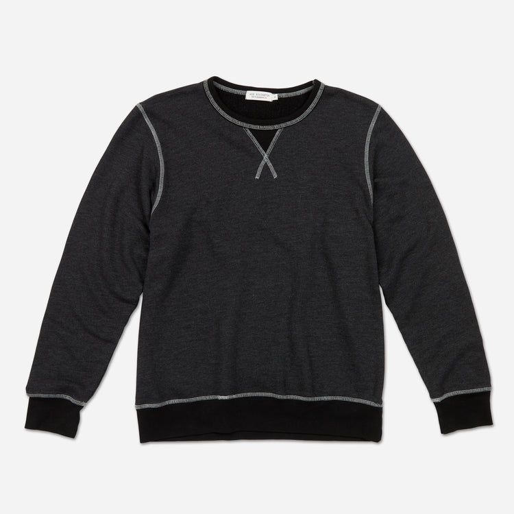 Fully extended frontal view of men's dark grey and black homespun french terry crew neck sweatshirt with white accent stitching