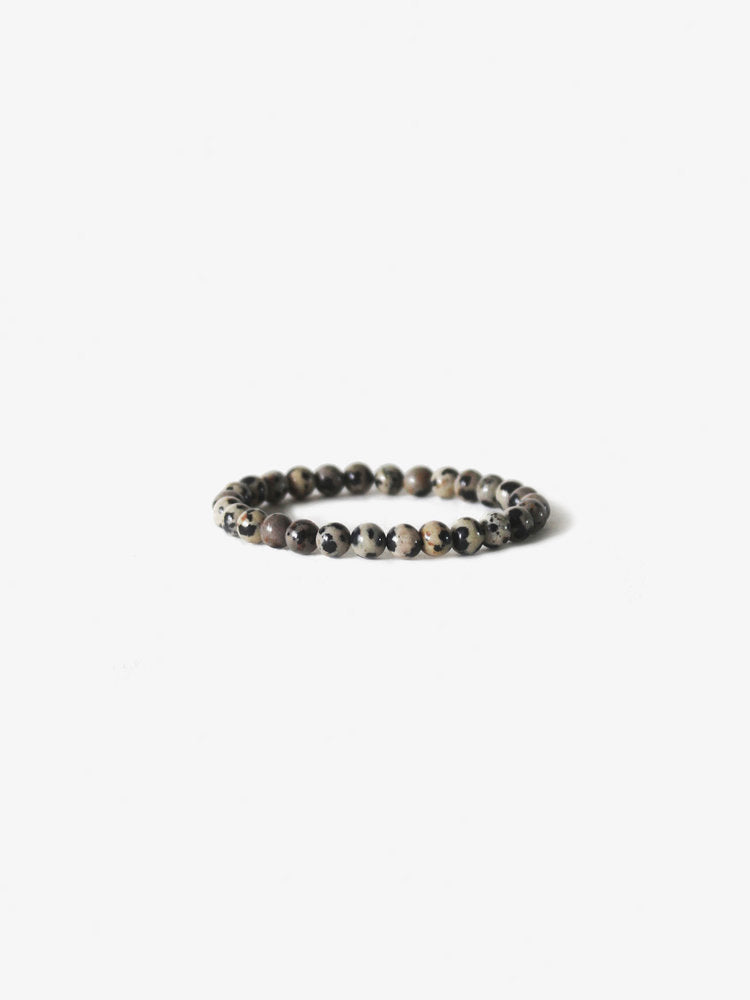 The Ace Rivington Branco - Earth Bracelet - Dalmatian Stone features round beige beads with black spots, inspired by the Dalmatian dog's coat, arranged in a simple, elegant circular pattern.