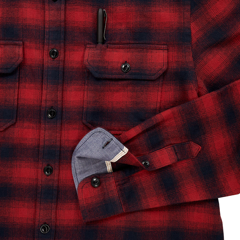close up of pocket with pen and sleeve cuff on men's black and red plaid pattern flannel with white collar stripe