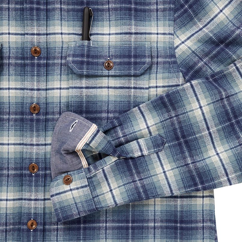 close up of pocket with pen and sleeve cuff on men's off white and light blue plaid pattern flannel with brown buttons and white collar stripe in standard height option