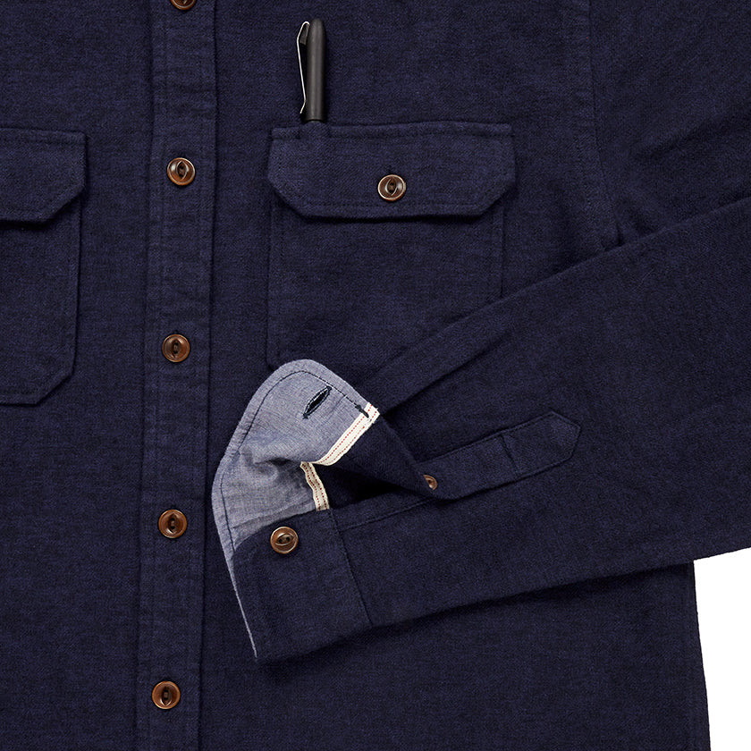 close up of pocket with pen and sleeve cuff on men's navy blue flannel with brown buttons and white collar stripe in standard height option