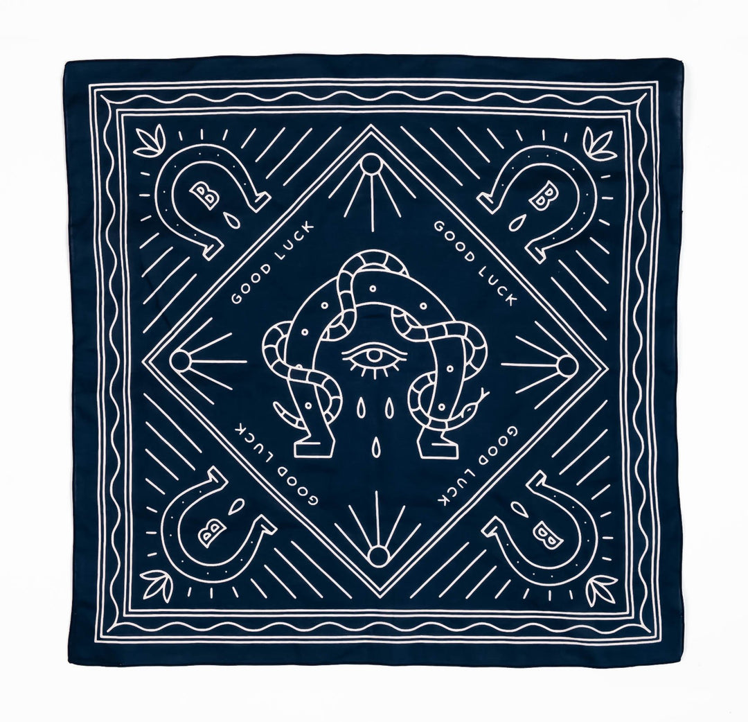 bandana print of snake wrapped around a horseshoe with an eye in the middle surrounded by four other horseshoes with Bs in the middle and the text good luck repeated