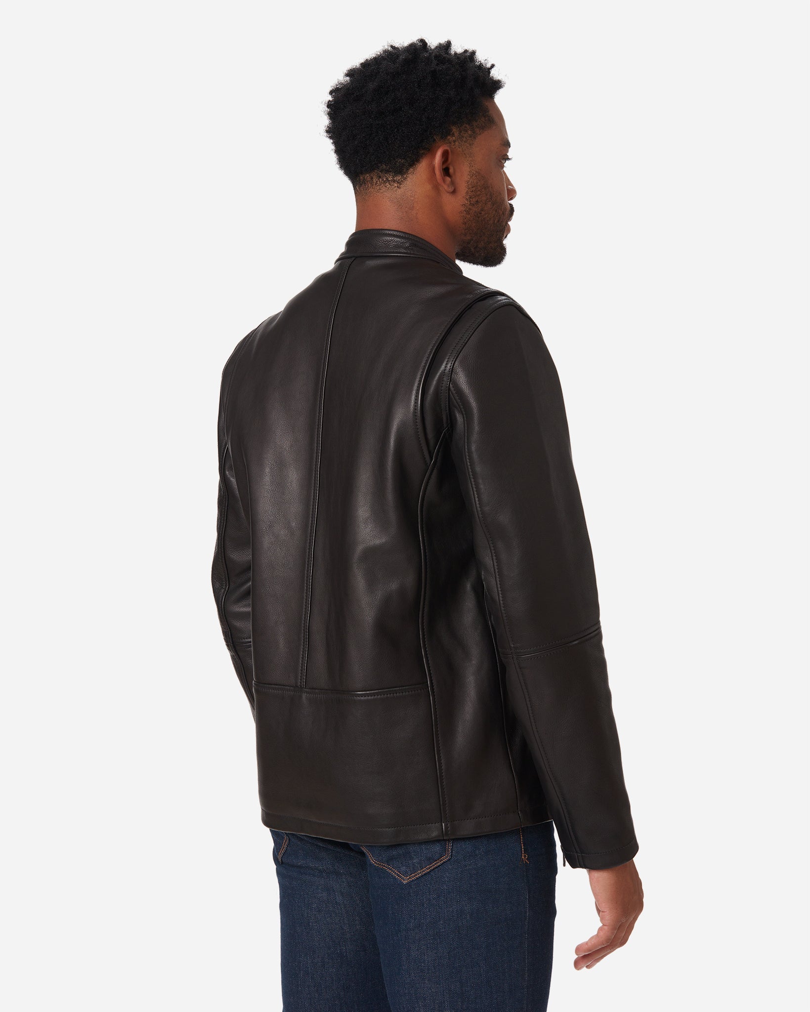 Back view of a man standing wearing an Ace Rivington Cowhide - Cafe Racer - Vintage Black Jacket lined with Black Chambray and finished with signature red piping details in blue jeans. 