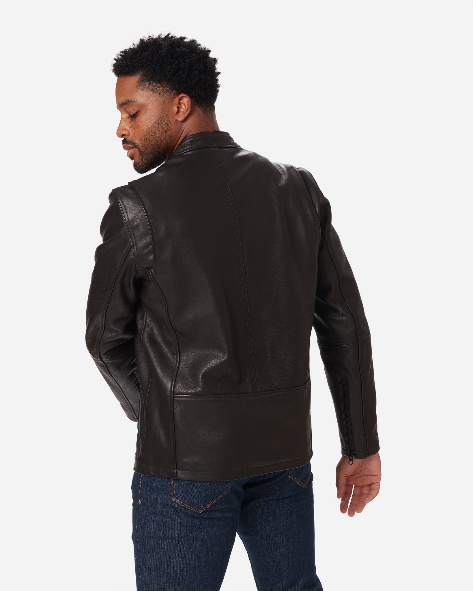 Back view of a standing man wearing a Cowhide - Cafe Racer Jacket - Vintage Black by Ace Rivington paired with blue jeans.
