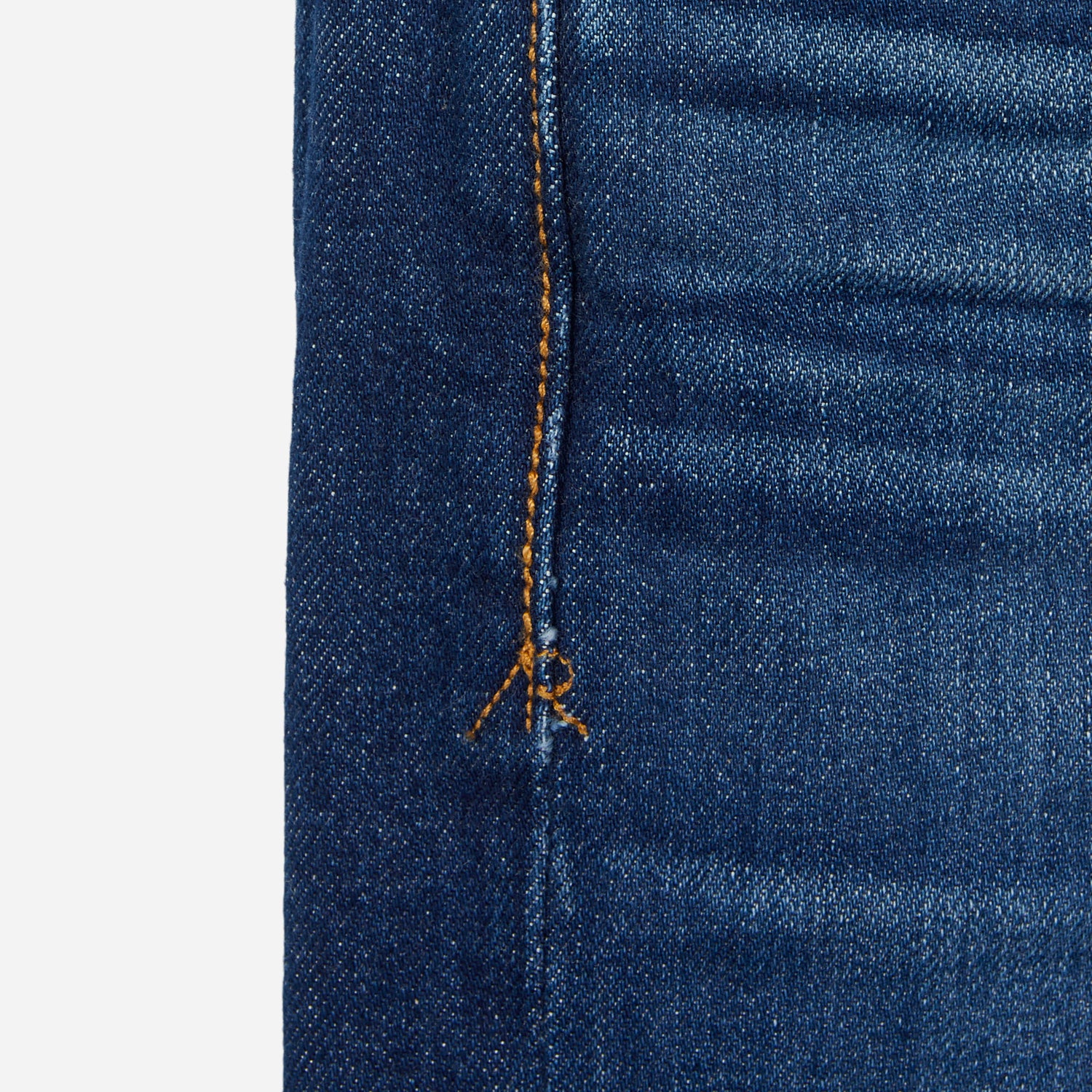 close up of stitching of pair of high quality slim cut men's dark blue jeans with slight wear