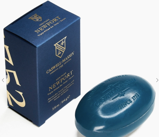 Ace Rivington Caswell-Massey Heritage Newport Triple-Milled Bar Soap in blue packaging. The soap is oval-shaped and dark blue, embossed with the brand name and 'Since 1752.' The box is also dark blue with gold text and accents, featuring the Caswell-Massey logo and product details.