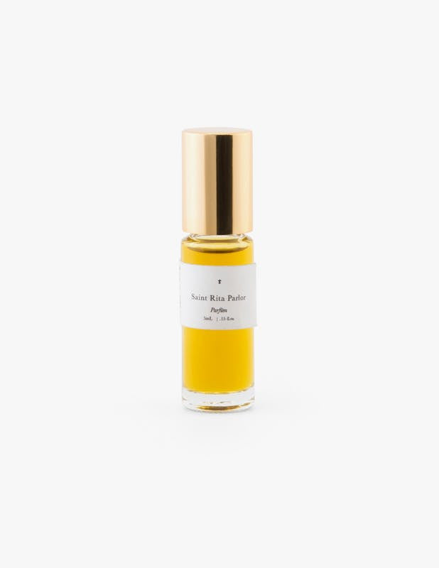A small glass bottle with a gold cap of Ace Rivington Saint Rita Parlor - Signature Parfum, containing 5 mL of yellow liquid. 